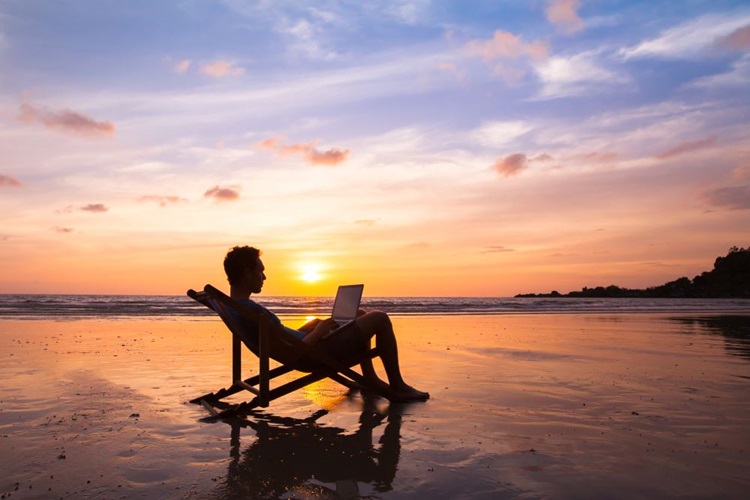 Mann sitzt im Liegestuhl am Strand